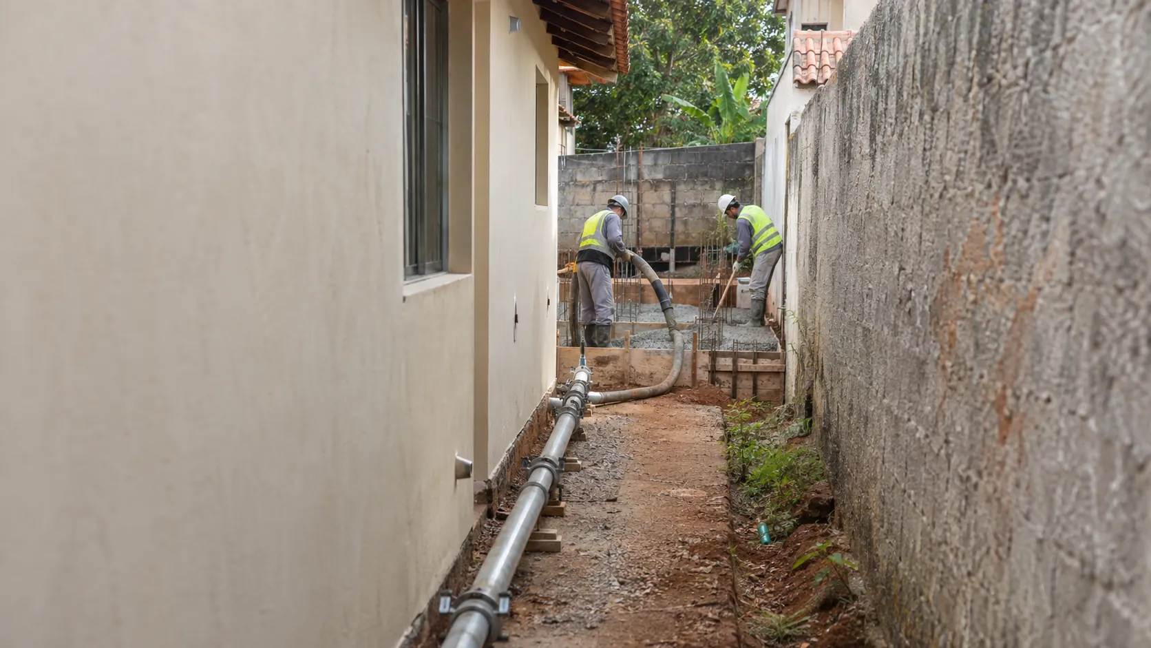 Tubulação da bomba ao longo do corredor lateral de uma casa até o fundo do terreno